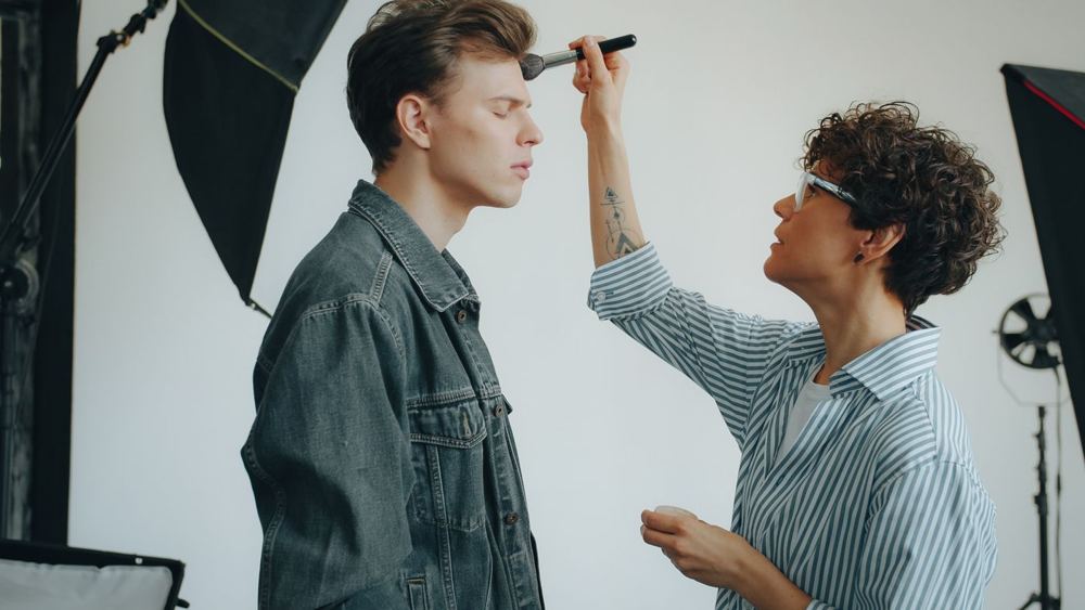 Wizażystka nakłada makijaż modelowi w studiu